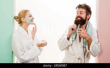 Procédures matinales. Couple homme et femme faisant l'hygiène du matin. Mari avec rasoir électrique, femme avec masque facial cosmétique. Soins du matin Banque D'Images