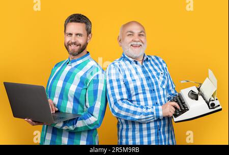 deux hommes heureux montrent contre la nostalgie en studio. les hommes montrent contre la nostalgie en arrière-plan. photo des hommes montrent contre la nostalgie avec ordinateur portable et rétro typewr Banque D'Images