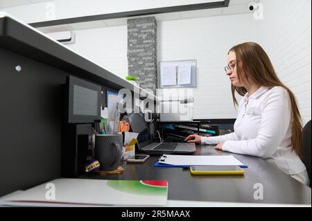 Portrait d'une femme administratrice à la réception, prenant rendez-vous avec le personnel médical assis sur un ordinateur portable Banque D'Images
