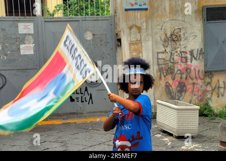 Naples, Italie, 4 juin 2023. Quartier de Forcella. Les personnes qui portent les couleurs de l'équipe regardent le dernier match du championnat sur un écran maxi sur la route, et ont un grand festin pour célébrer le club de football de Naples, qui est le vainqueur du championnat italien 2022-2023. Tous les habitants de Forcella prennent part à la fabrication de errymaking, à la consommation, à la nourriture et au chant. Les rues, comme toutes les rues de Naples, sont décorées de festons bleus, les couleurs de l'équipe. Les enfants et les adultes sont des bombes et des pétards légers. Crédits : Ferdinando Piezzi/Alay Live News Banque D'Images