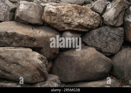 Gros plan de grosses roches ou de gros blocs. Grandes granites multicolores. Détails de grandes structures en pierre grise avec des particules d'orange qui brillent dans la lumière du soleil. S Banque D'Images