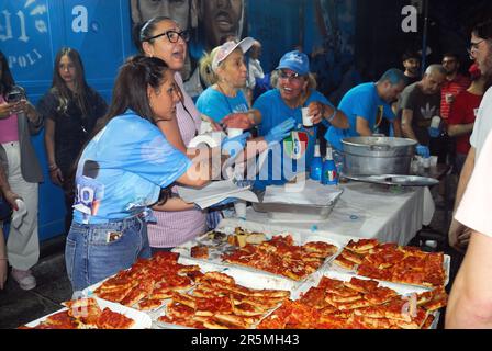 Naples, Italie, 4 juin 2023. Quartier de Forcella. Les personnes qui portent les couleurs de l'équipe regardent le dernier match du championnat sur un écran maxi sur la route, et ont un grand festin pour célébrer le club de football de Naples, qui est le vainqueur du championnat italien 2022-2023. Tous les habitants de Forcella prennent part à la fabrication de errymaking, à la consommation, à la nourriture et au chant. Les rues, comme toutes les rues de Naples, sont décorées de festons bleus, les couleurs de l'équipe. Les enfants et les adultes sont des bombes et des pétards légers. Crédits : Ferdinando Piezzi/Alay Live News Banque D'Images