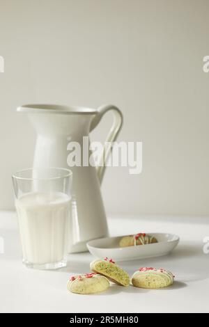 Composition avec biscuits maison au pain d'épice à la menthe avec matcha et fraises sublimées dans une assiette, verre de lait, pot et fleurs sauvages dans un vase sur la ba Banque D'Images