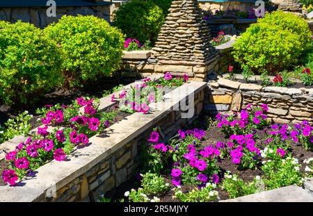 Aménagement paysager avec murs de soutènement et parterres de fleurs dans l'arrière-cour de la maison résidentielle. Aménagement paysager du jardin haut de gamme de la maison en été. Fleurs et plantes o Banque D'Images