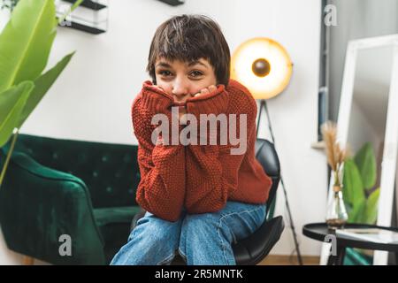 Jolie femme dans un pull brun pendu avant avec ses coudes posés sur ses genoux. Entraîneur jaune en arrière-plan. Photo de haute qualité Banque D'Images