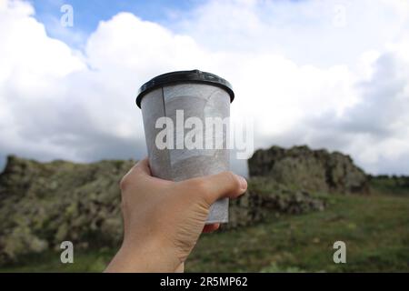 tasse de café ou de thé dans la main de l'homme. la consommation de liquides dans la nature. Banque D'Images