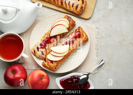 Pâte fraîche savoureuse avec confiture et pommes servies sur une table texturée blanche, à plat. Espace pour le texte Banque D'Images