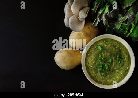 Purée de soupe, légumes frais, champignons et légumes verts sur fond noir. Encore la vie. Photo de nourriture avec espace pour le texte Banque D'Images