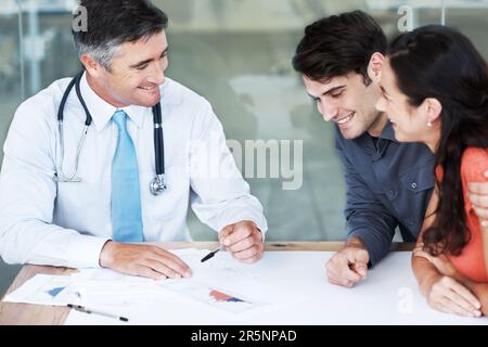 Vous êtes tous les deux en grande forme... Un jeune couple rencontre un médecin pour un diagnostic positif. Banque D'Images