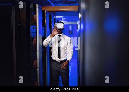 Découvrez l'avenir de la connectivité. Un jeune homme portant un casque VR pendant qu'il travaille dans une salle de serveurs. Banque D'Images