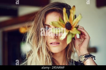 Ne perdez pas votre côté sauvage. Portrait d'une jeune femme libre et animée posant dans un magasin de bord de route avec une fleur. Banque D'Images