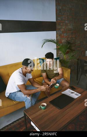 Nous proposons les meilleures idées que le café. deux jeunes hommes utilisant une tablette numérique tout en étant assis dans un café. Banque D'Images