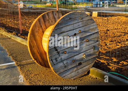 grande bobine en bois pour enrouler un fil ou un câble haute tension. bobine en bois jaune et lisse, enroulement de fil. outil pour l'électricité. avec des trous autour du pe Banque D'Images