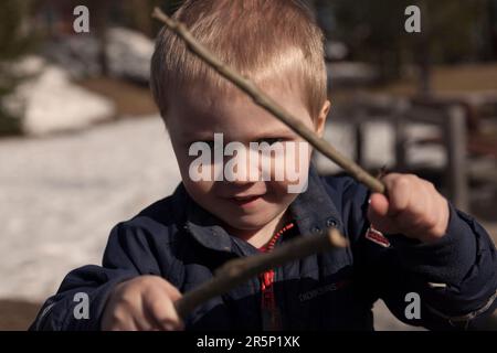Umea, Norrland Suède - 17 avril 2021 : le petit garçon est en clôture avec des bâtons Banque D'Images