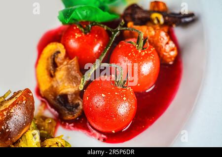 Une assiette de fruits et légumes frais et sains : tomates cerises, champignons et sauce aux baies - parfait pour le bien-être. Banque D'Images