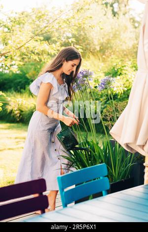 Jolie jeune femme arrosoir des plantes dans le jardin d'été Banque D'Images