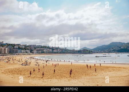 Foule de personnes appréciant des vacances d'été sur la plage de sable de la Concha contre des immeubles d'appartements le jour ensoleillé à Donostia San Sebastian, pays Basque, S Banque D'Images