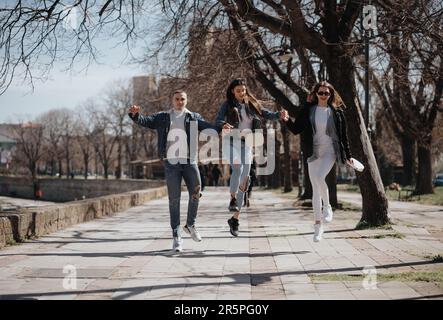 Trois amis proches s'amusent tout en sautant et en marchant dans le parc Banque D'Images