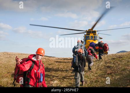 Les membres de l'équipe de sauvetage de Langdale/Ambleside Mountain dirigent les marcheurs sauvés vers la sécurité, vers un hélicoptère RAF Sea King en attente après qu'ils aient été sauvés hors de Dungeon Ghyll dans le Banque D'Images