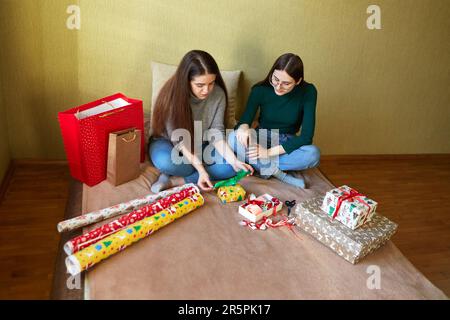 Deux jeunes femmes avec emballage cadeau du nouvel an à la maison sur le lit Banque D'Images