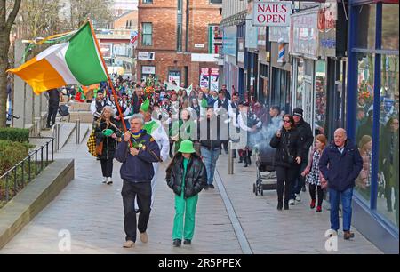 Les membres de la communauté irlandaise Warrington marchent le long de Bridge Street en transportant le tricolore irlandais pendant les célébrations de la Saint Patrick en mars 2023 Banque D'Images
