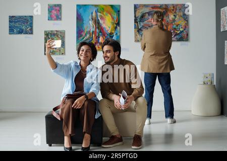 Jeune couple faisant le portrait de selfie sur smartphone dans la galerie d'art moderne Banque D'Images