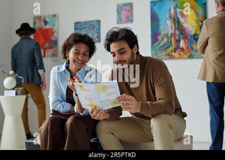 Jeune couple multiethnique lisant la brochure lors de leur visite à la galerie d'art Banque D'Images