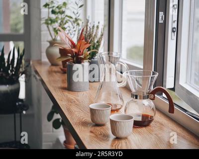 Une variété d'ustensiles de cuisine pour le café sur un comptoir en bois avec des plantes en pot Banque D'Images