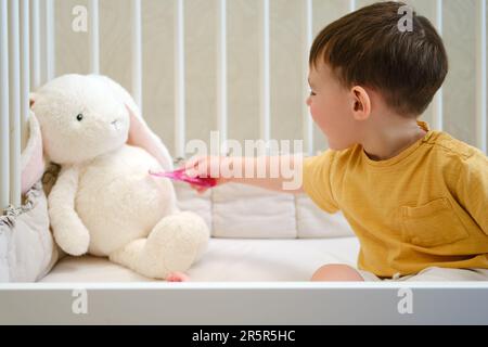 Le bébé est heureux de montrer à son petit ami comment brosser ses dents correctement pour une santé bucco-dentaire optimale. Enfant âgé d'environ deux ans (un an onze mois Banque D'Images