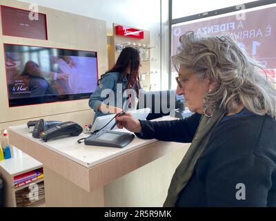 Fidenza, Italie - Mai 2023 franchise Vodafon à Fidenza, Italie. une femme senior signe un contrat de tablette numérique avec un fournisseur de communication mobile. Banque D'Images