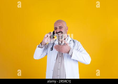 Docteur blanc caucasien parlant au téléphone. Heureux médecin portant l'uniforme hospitalier, stéthoscope. Lol. Parler avec un ami, visage joyeux. Banque D'Images