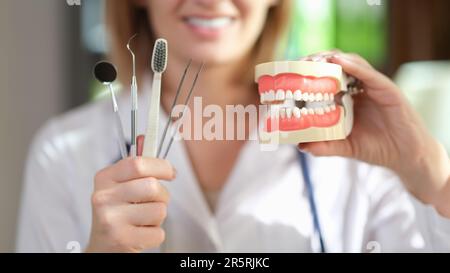 Le dentiste montre le modèle de mâchoires et les outils de soins dentaires à l'hôpital Banque D'Images