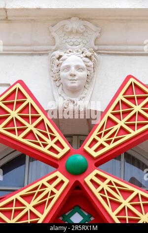 France, Meurthe et Moselle, Nancy, ornement mascaron et moulin à vent utilisé comme enseigne de restaurant sur une façade de la place Stanislas (place Stanislas ancienne place royale) construite par Stanislas Leszczynski, roi de Pologne et dernier duc de Lorraine au 18e siècle, classée au patrimoine mondial de l'UNESCO Banque D'Images