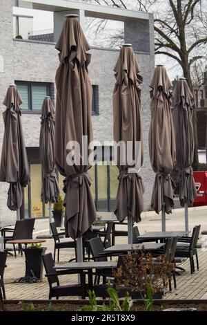 Un coin salon extérieur avec des tables et des parasols à proximité d'une façade moderne Banque D'Images