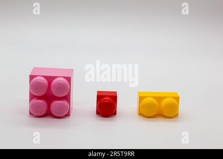 Constructeur de jouets pour enfants lego différentes tailles. Blocs rouge, rose et jaune et vert. Photo de haute qualité. Isolé. Banque D'Images