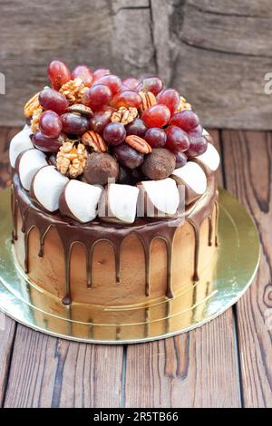 L'idée d'un gâteau d'automne fait de chocolat et décoré de raisins, de noix, de truffes au chocolat et de guimauves. Rustique backgrond, cuisine de confort Banque D'Images