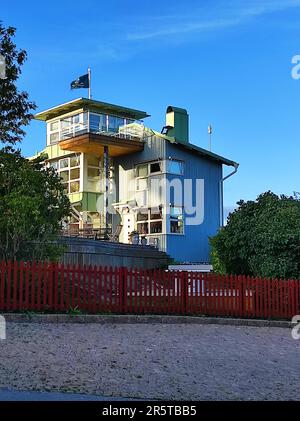 Une maison de deux étages avec un grand toit ouvert se trouve sur une colline vallonnée luxuriante, entourée d'un paysage paisible de champs et d'arbres Banque D'Images