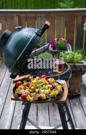 prêt à manger - un verre de vin et des crevettes grillées avec du saumon et des légumes sur une assiette noire, d'un barbecue lors d'une journée d'été sur le balcon Banque D'Images