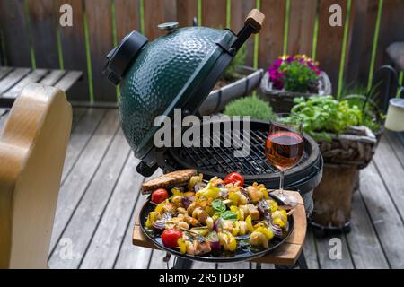 prêt à manger - un verre de vin et des crevettes grillées avec du saumon et des légumes sur une assiette noire, d'un barbecue lors d'une journée d'été sur le balcon Banque D'Images