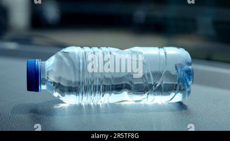 une bouteille d'eau minérale sur le tableau de bord de la voiture. De l'eau embouteillée a été laissée dans la voiture pendant longtemps. Banque D'Images