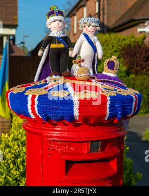 Sussex, Royaume-Uni - 30 avril 2023 : un surmontoir de boîte postale tricoté sur une boîte postale rouge dans le village de Cowfold à West Sussex, Royaume-Uni. Banque D'Images