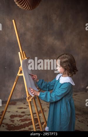 une petite fille mignonne tire derrière un chevalet. rêvant Banque D'Images