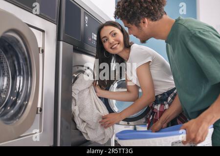 Happy couple linge pliant ensemble à la laverie automatique lave-linge intérieur Banque D'Images