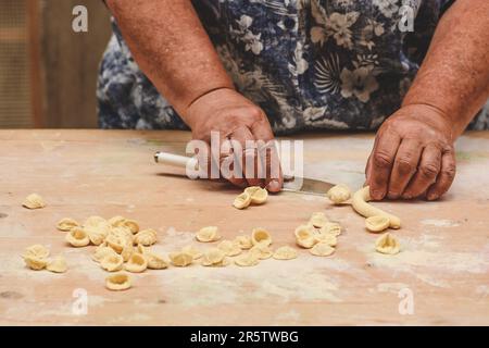 Mains d'une femme locale dans la rue de la vieille ville de Bari faisant orecchiette ou orecchietta, pâtes faites à la main avec du blé dur et de l'eau typique Puglia Banque D'Images