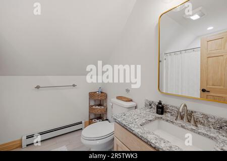 La salle de bains moderne est dotée de toilettes blanches et d''une armoire en bois aux murs blancs Banque D'Images
