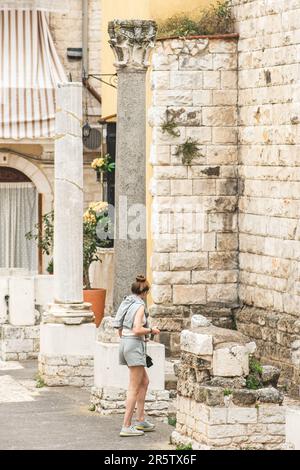 Belle fille marchant parmi les vestiges et les colonnes d'un temple romain dans la vieille ville de Bari, Puglia, Italie, verticale Banque D'Images