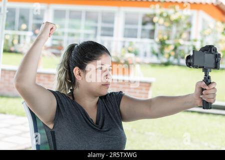 jeune latina influenceur fille, avec caméra dans la main enregistrement de contenu tout en pointant vers l'arrière Banque D'Images