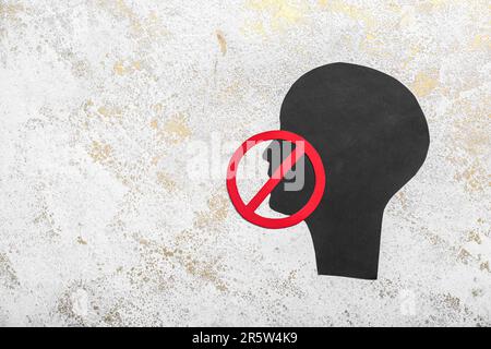 Tête humaine en papier avec signe d'interdiction sur fond de gringe. Concept de censure Banque D'Images
