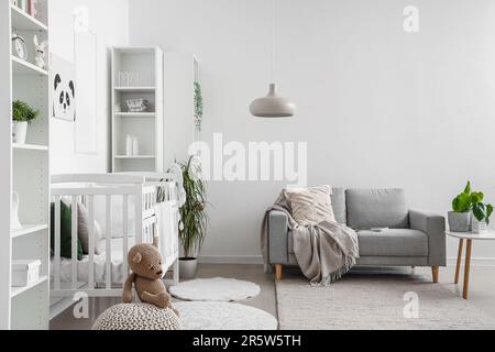 Intérieur élégant de la chambre des enfants dans des tons blancs avec lit bébé et étagère Banque D'Images