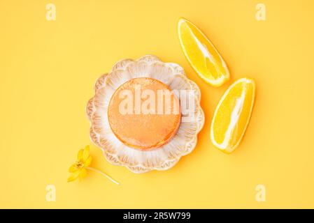 Plaque avec barre de shampooing solide, fleur et orange sur fond de couleur Banque D'Images